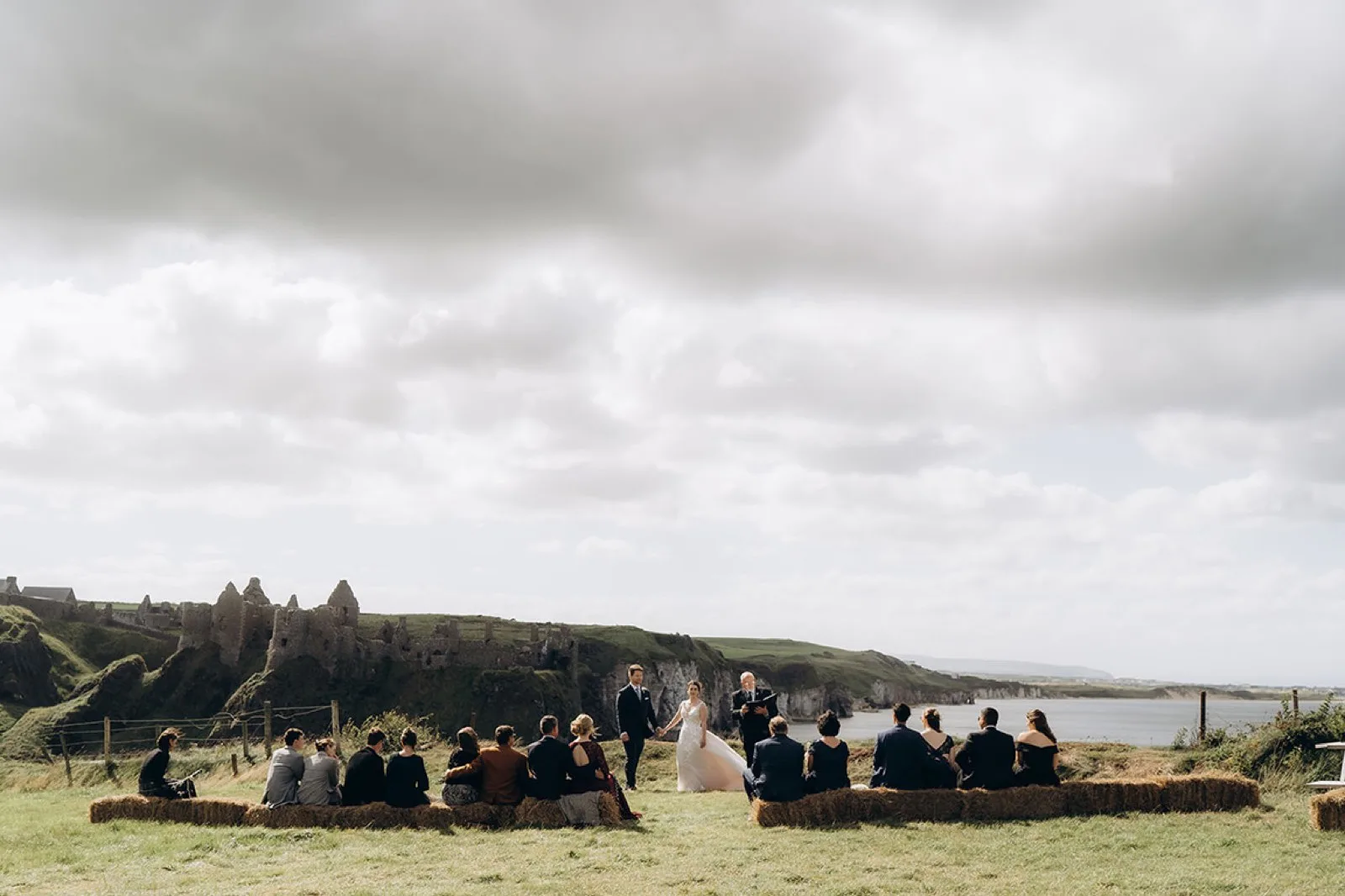 Wedding ceremony in the Dunluce Farm meadow with the castle and coast beyond